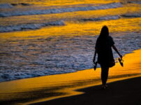 夕暮れの浜辺を女性が静かに歩く情景｜懐かしい情景が静かによみがえる、やさしい記憶のイメージ写真