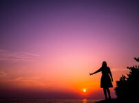 夕暮れの海辺でシルエットの女性がそっと手を伸ばす情景｜懐かしい情景が静かによみがえる、やさしい記憶のイメージ写真