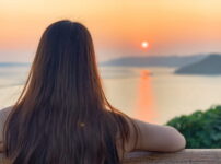 夕暮れの海を静かに見つめる女性の後ろ姿｜懐かしい情景が静かによみがえる、やさしい記憶のイメージ写真