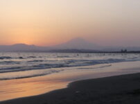 夕暮れの海辺に柔らかな光が広がり、遠くに富士山が静かに浮かぶ風景｜懐かしい情景が静かによみがえる、やさしい記憶のイメージ写真