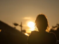 夕暮れの光に包まれて立ち止まる女性の後ろ姿｜懐かしい情景が静かによみがえる、やさしい記憶のイメージ写真