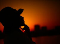 夕暮れの空を背景に、大人の女性が静かに佇むシルエットの情景｜懐かしい情景が静かによみがえる、やさしい記憶のイメージ写真